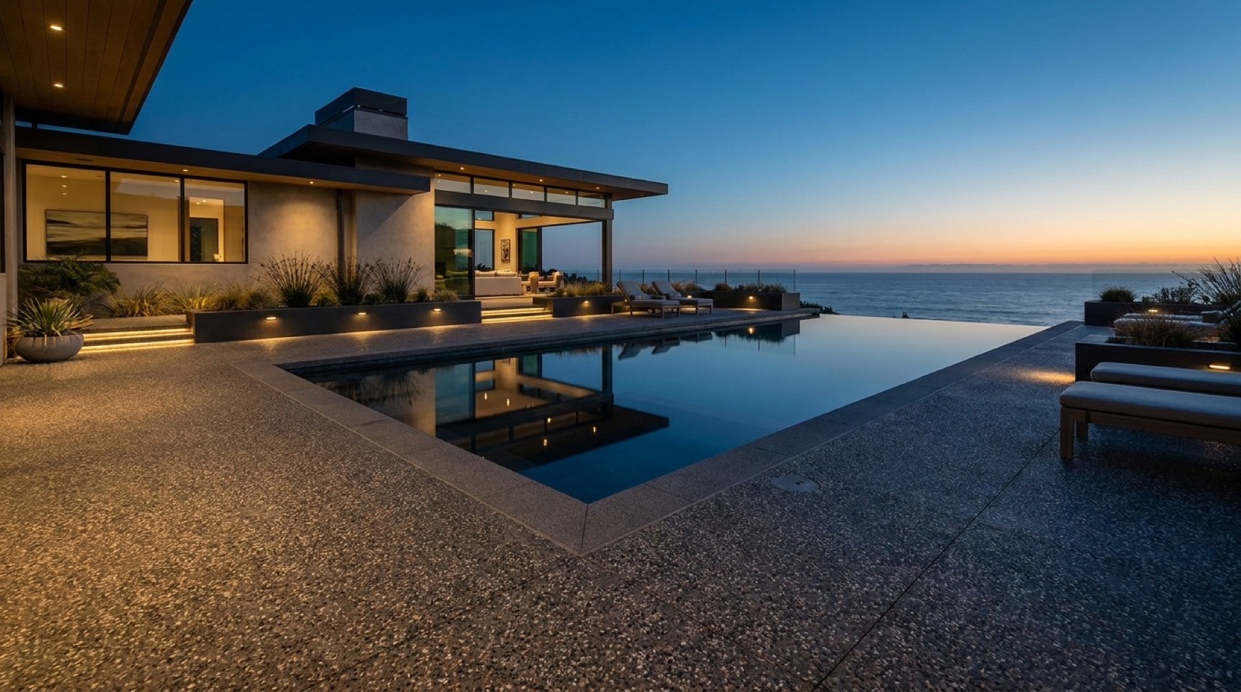 An exposed aggregate surround beside a pool at dusk