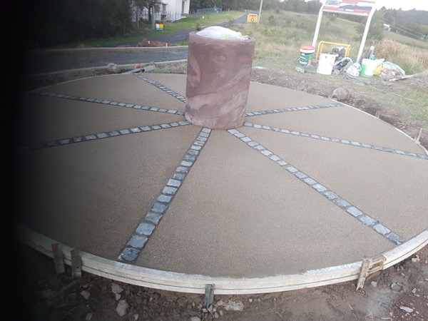 A circular concrete feature slab with brick paver spokes
