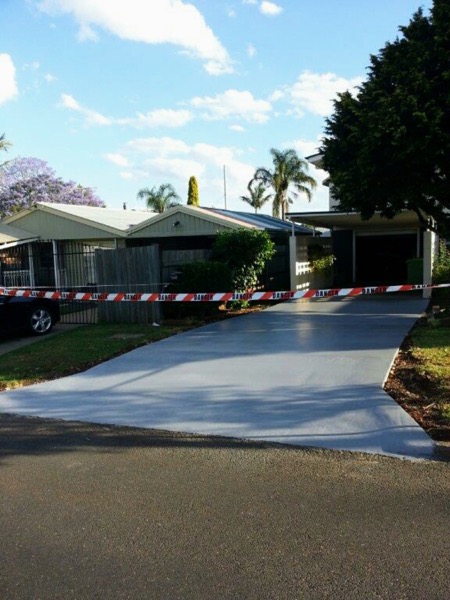 A freshly poured grey concrete driveway with barrier tape across it