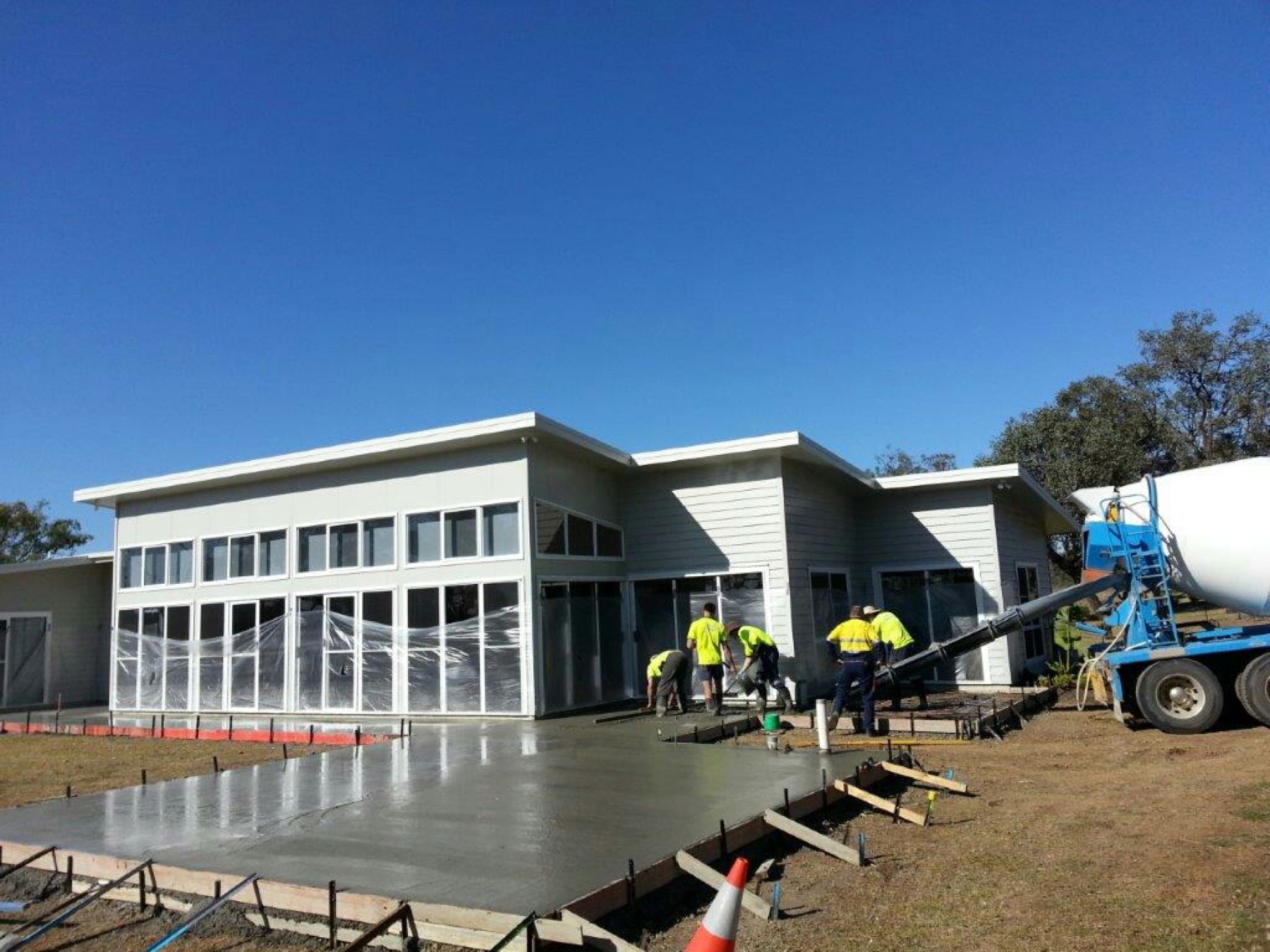 A crew screeding a large commercial slab beside a new building