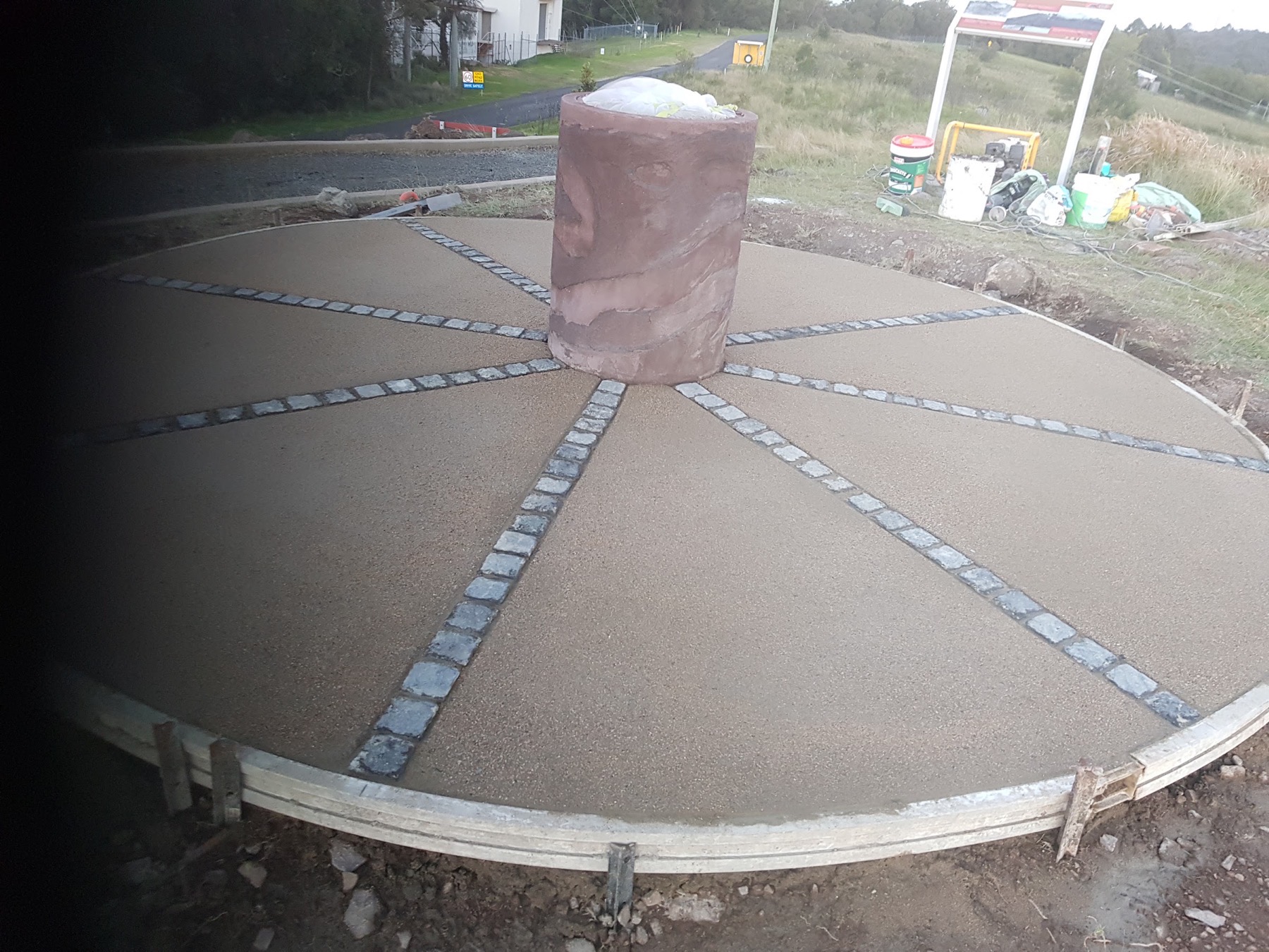 A circular concrete feature slab with brick paver spokes