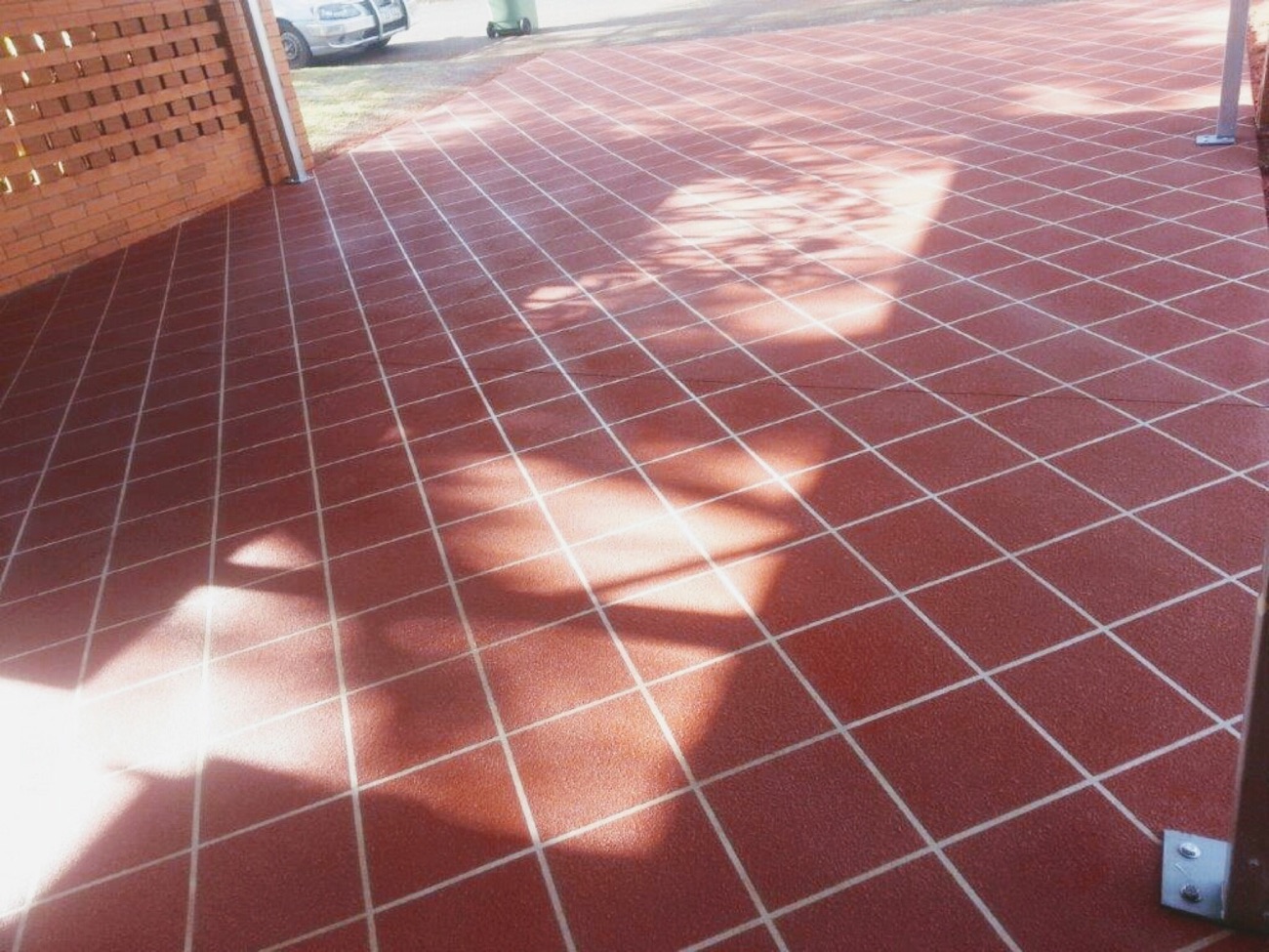 A red brick-pattern stencilled concrete patio beside a brick wall