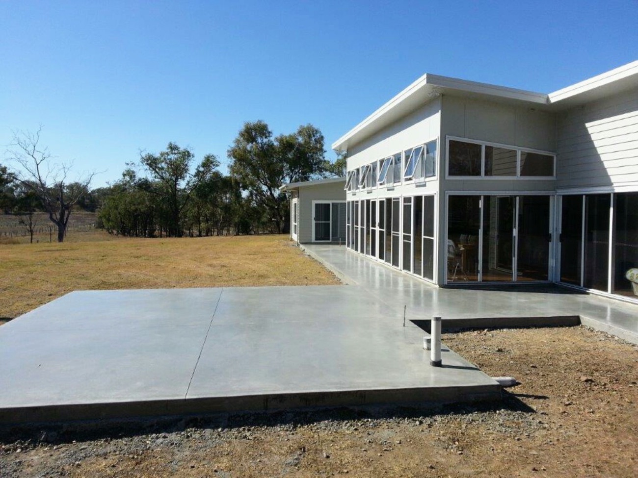 A concrete slab running along the side of a modern shed
