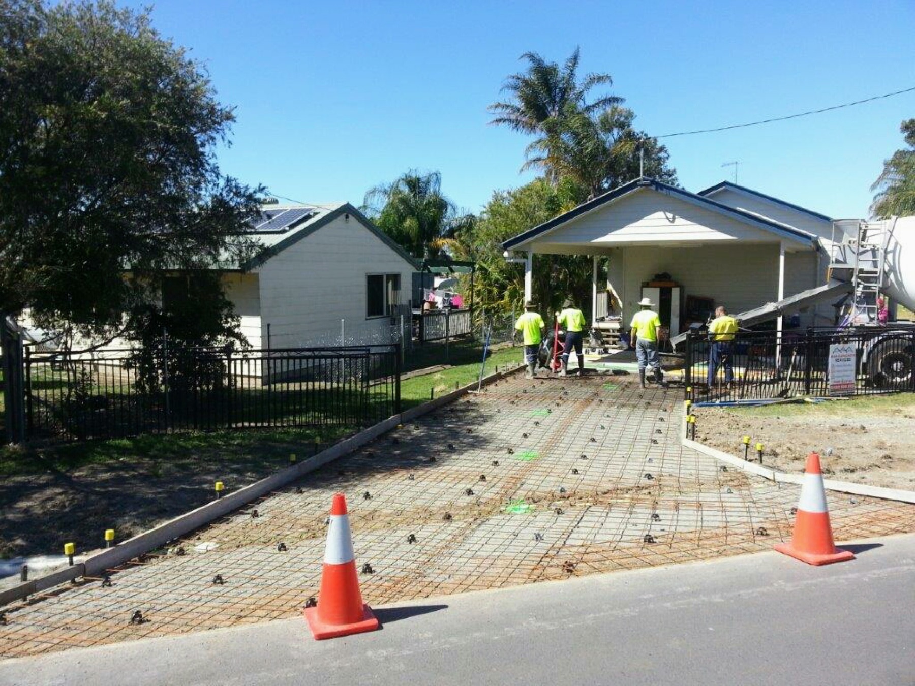 A driveway prepared with steel mesh while the crew works beside a concrete truck