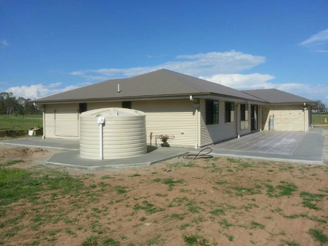 A house with a rainwater tank and a concrete slab along the side